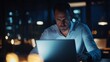 © nikomsolftwaer - Late night focus man working on laptop in urban office technology cozy environment intimate viewpoint productivity concept