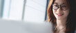 © tippapatt - Close-up, young asian business woman with eyeglasses working on laptop computer. Video call using laptop for online meeting and video conference from home office