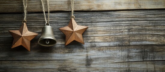 Aufkleber - Artistic metallic stars and bell hanging on rustic wooden background enhancing seasonal decor and warmth in interior design