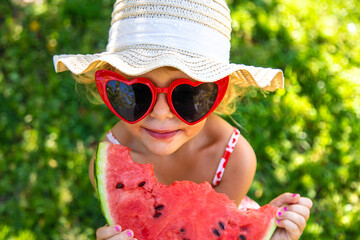 Poster - Child eating watermelon in the garden. Selective focus.