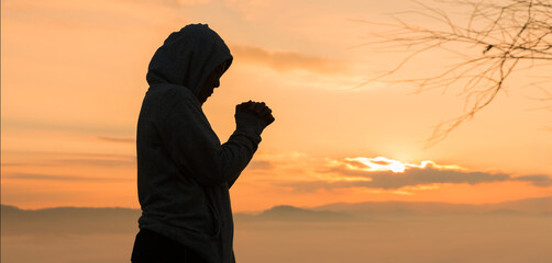 Wall Mural - Christian woman raised her hand in worship and prayer to God, seeking peace through Jesus Christ during a serene sunrise morning. worship, christian, jesus christ, hand, god, peace, pray, sunrise.