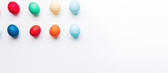 Fototapete - Vibrant assortment of colored Easter eggs arranged on a white backdrop with ample empty space for seasonal text or messaging.