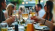 © ryker - lively gathering of friends enjoying meal outdoors, with glasses of white wine raised in toast, creating warm and joyful atmosphere