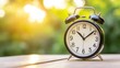 © Molesay - Classic alarm clock on wooden surface, outdoor setting.