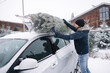 © Aleksandr - Handsome man tying to put a Christmas tree to the roof of the car to bring it home. Live fir tree delivery