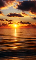 Wall Mural - vertical view of the sun setting over the ocean, casting a warm glow on water with cloudy sky