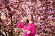 © anatoliy_gleb - Woman allergic using medical nasal drops, suffering from seasonal allergy at spring in blossoming garden. Young woman treating runny nose in front of blooming tree outdoors. Spring allergy concept.