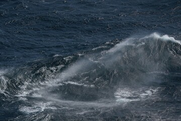 Wall Mural - dark ocean waves crashing with powerful force, creating mist and foam. turbulent sea showcases natur