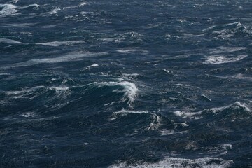 Wall Mural - dark ocean waves with white foam creating dynamic seascape. turbulent water reflects moody atmospher