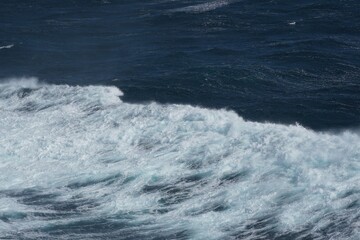 Wall Mural - waves crashing on deep blue ocean create dynamic and powerful scene. contrast between white foam and
