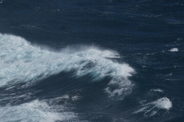 Wall Mural - powerful ocean waves crashing against shore create dramatic scene. deep blue water contrasts with wh