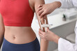 © New Africa - Doctor measuring woman's body fat with caliper in clinic, closeup