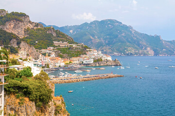 Wall Mural - The photo captures the stunning Amalfi Coast from a cruise ship deck, showcasing dramatic cliffs, charming villages, and lush landscapes against the turquoise sea and vibrant blue sky.