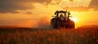 © miss irine - Red tractor plows field at sunset. Farmer drives powerful machine across golden crop. Dust rises behind vehicle. Rural agriculture scene. Farm equipment in countryside.