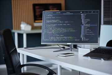image of a modern office workspace featuring a computer monitor displaying software code and various