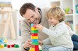 © SerPak - A father and his young son enjoy quality time together as they build a colorful tower using wooden blocks. The joyful atmosphere is enhanced by the bright lighting and cheerful surroundings filled wit