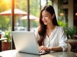 © miss irine - Young Asian woman uses laptop at outdoor cafe. She works remotely. Freelancer enjoys sunny day. Travel lifestyle. Happy businesswoman. Summer vacation.