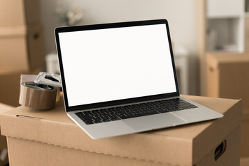 close up shot of laptop computer with white blank display placed on cardboard box in e-commerce stor