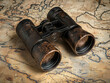 © AndyGordon - Vintage binoculars on a weathered map with travel memorabilia