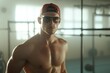© Atlas Studio - Fitness model posing confidently in gym with sunglasses and cap during workout session