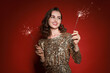 © New Africa - Smiling woman with sparklers celebrating Christmas on red background