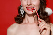 © New Africa - Smiling woman holding Christmas candy cane on red background, closeup. Space for text
