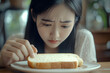 © HNXS Digital Art - Concerned woman examining piece of white bread, emotional expression at home