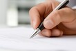 © Slamet - Close-up of a hand signing a document with a pen.