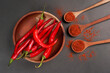 © AndhikaRaya - Large red chili and chilli powder served on wooden bowk isolated on a black background