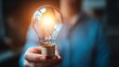 © Mariya - Hand Holding Glowing Light Bulb Symbolizing Ideas Innovation Creativity Inspiration Business