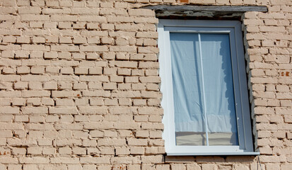 Wall Mural - A window with a white curtain is shown against a brick wall