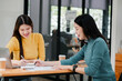 © Satori Studio - Two young women working together at a desk with laptops and coffee, showcasing teamwork in a modern office setting.
