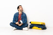 © luismolinero - Caucasian handsome man with a suitcase full of clothes sitting on the floor at indoors thinking an idea while looking up