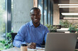 © ty - Portrait of young african man sitting at his desk in the office.