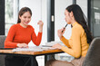 © kenchiro168 - Two women engaged in collaborative discussion at modern office table, sharing ideas and reviewing documents. Their expressions reflect enthusiasm and teamwork