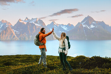Wall Mural - couple hikers traveling with backpack hiking in norway mountains, man and woman high five hands on a