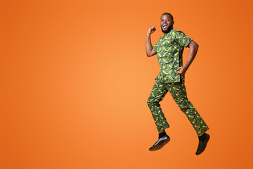 Wall Mural - Joyful black man happily jumping up over yellow studio background