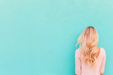 Wall Mural - Woman with long blonde hair standing against a bright blue wall in a relaxed pose