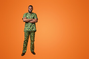 Wall Mural - Smiling african american guy in authentic costume posing over yellow background, holding arms crossed