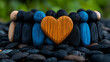 © Butsarakham - A circle of colorful wooden figures surrounds a large orange heart, symbolizing unity, love, and community against a backdrop of smooth black pebbles.