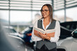 © Zamrznuti tonovi - Confident woman holding book in modern vehicle showroom