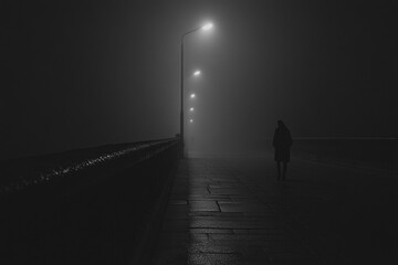 Aufkleber - A person walks along a deserted bridge shrouded in fog, illuminated only by the faint glow of streetlights at night. Generative AI