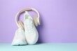 © New Africa - Pair of stylish white sneakers and headphones on color background, space for text