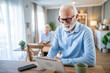 © Miljan Živković - senior man use digital tablet for online video call wife sit behind
