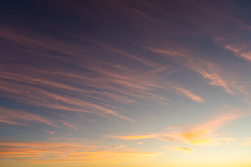 Wall Mural - warm blue sky with colorful light pink and yellow cirrus clouds at sunset. abstract texture backgrou