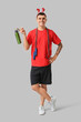 © Pixel-Shot - Young happy man in reindeer horns with skipping rope and bottle of water on grey background