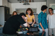 © qunica.com - A joyful gathering of young friends in a modern kitchen, laughing and enjoying each other's company during a casual meet-up.