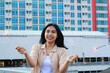© M Alfan Setyawan - carefree asian young woman holding sparkler celebrate new year eve with laugh and dance in rooftop apartment outdoor with city building background
