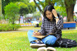 © M Alfan Setyawan - beautiful asian young woman college student focused writing on notebook and reading book in outdoors city park