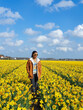 © Fokke Baarssen - A woman enjoys a sunny day among vibrant yellow daffodils in a blooming field